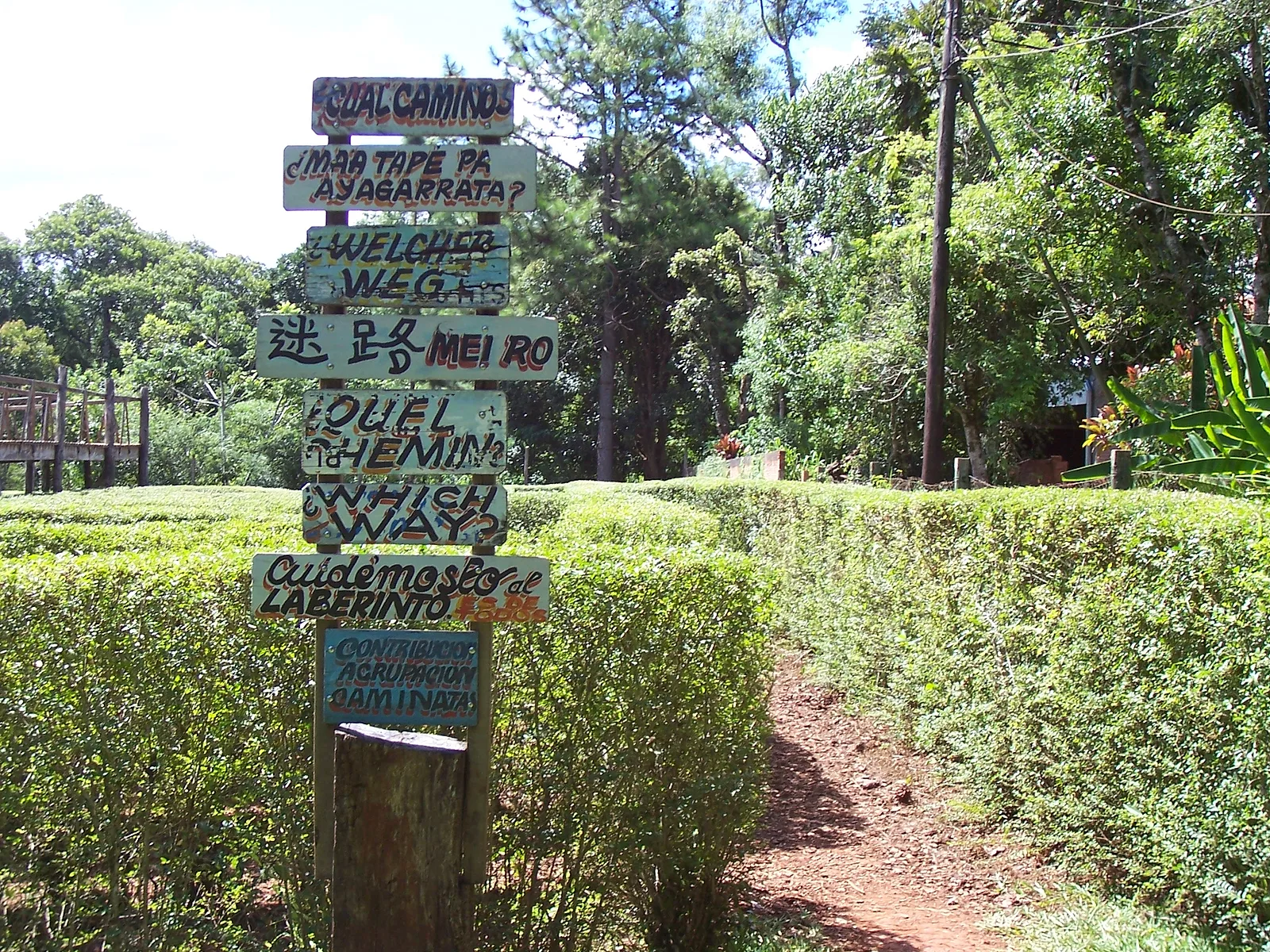 Entrada al laberinto vegetal, con carteles de madera en varios idiomas
